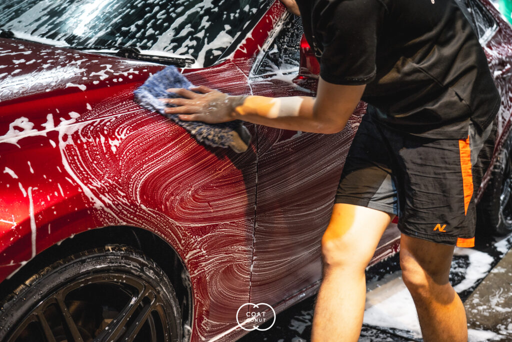 Paint protection film being applied to the panel of a red car