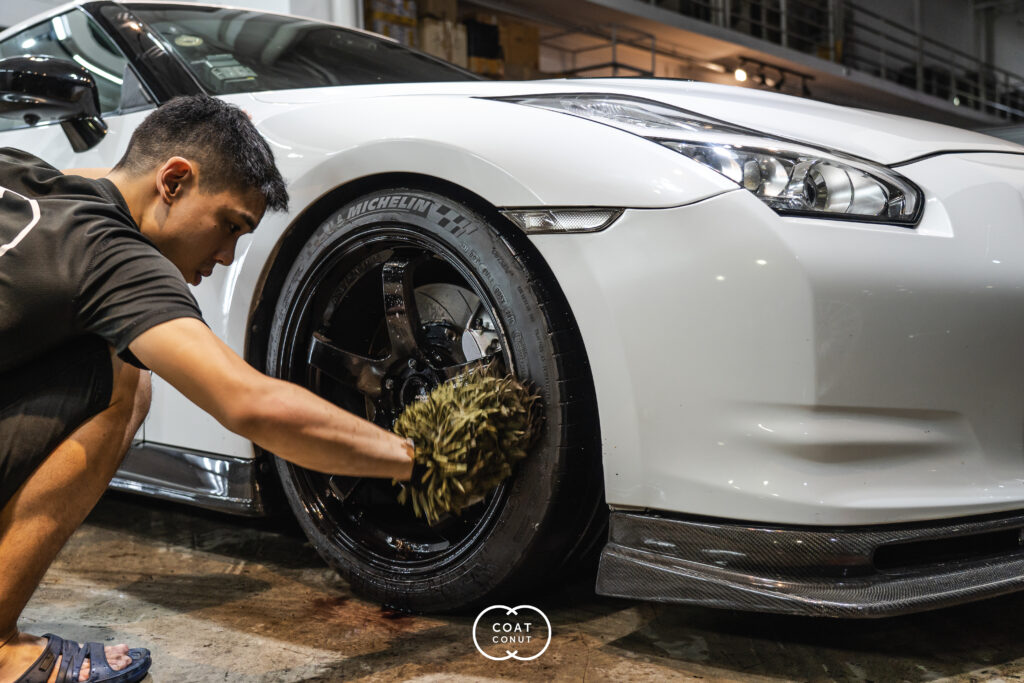 Hand detailing a wheel rim with a brush